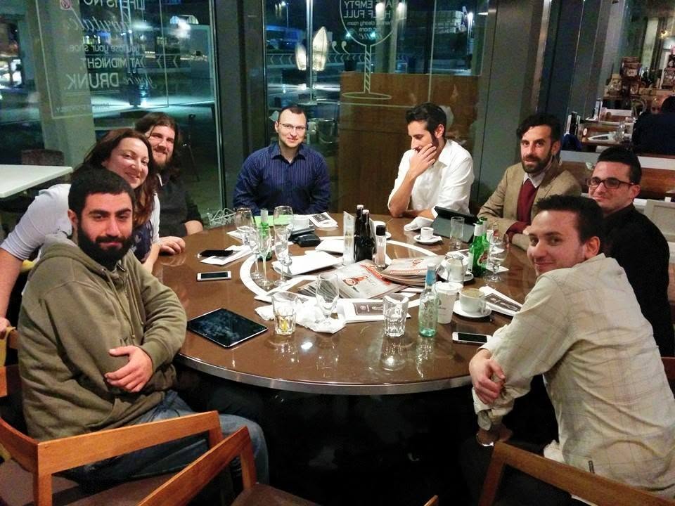 A group of people gathered around a round table in a café at night
